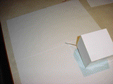 GIF of a handmade paper cube rolling on a piece of paper